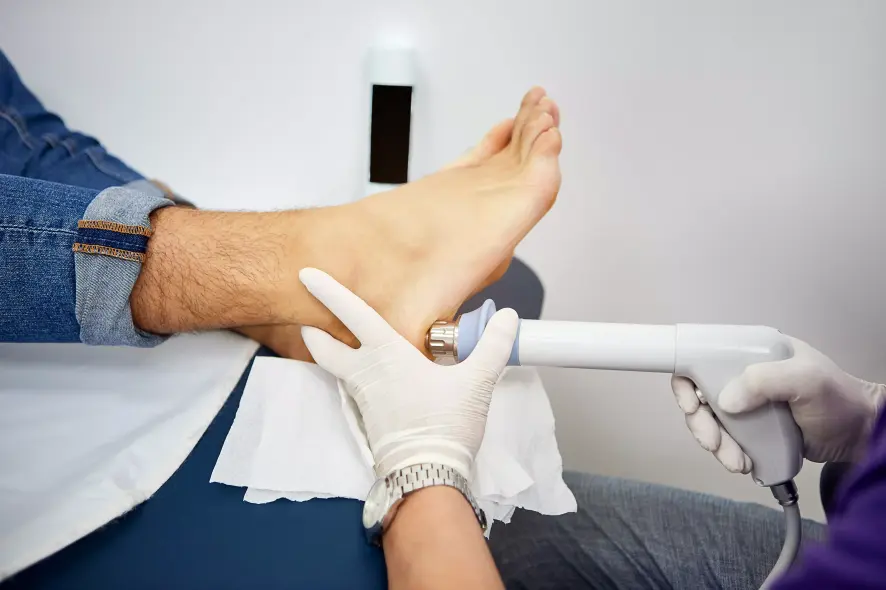 Mann erhält Stoßwellentherapie gegen Fersensporn am Fuß