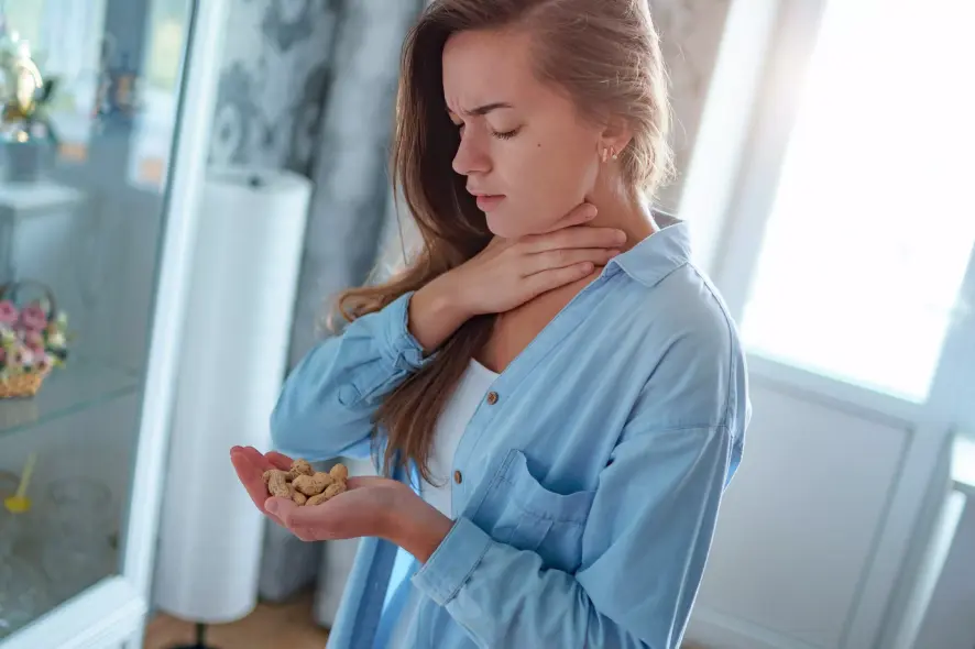 Lebensmittelunverträglichkeit junge Frau hält Erdnüsse in der Hand und die andere an ihren Hals